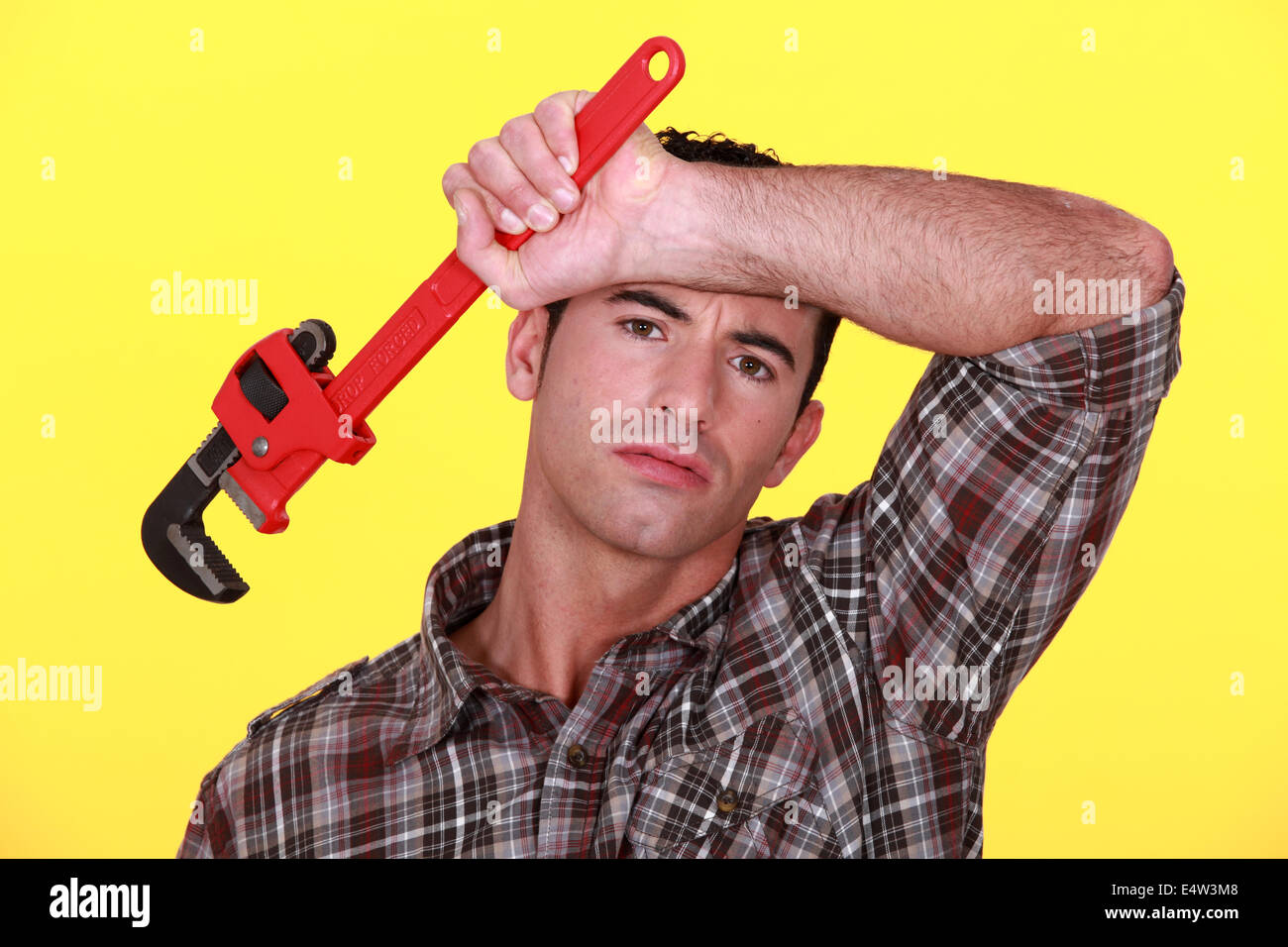 Tired worker holding wrench Stock Photo Alamy