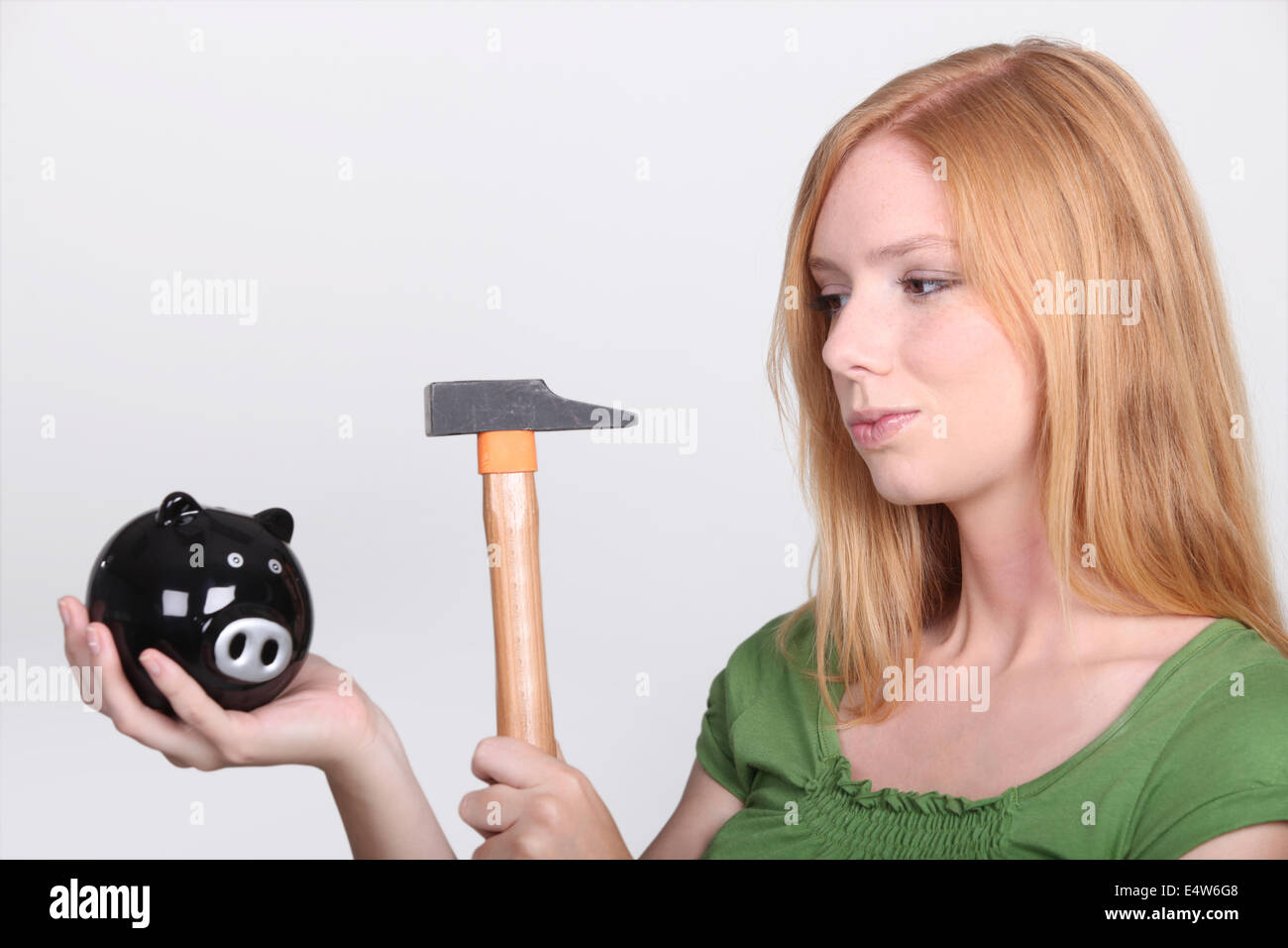 Young woman holding piggy bank and hammer Stock Photo - Alamy