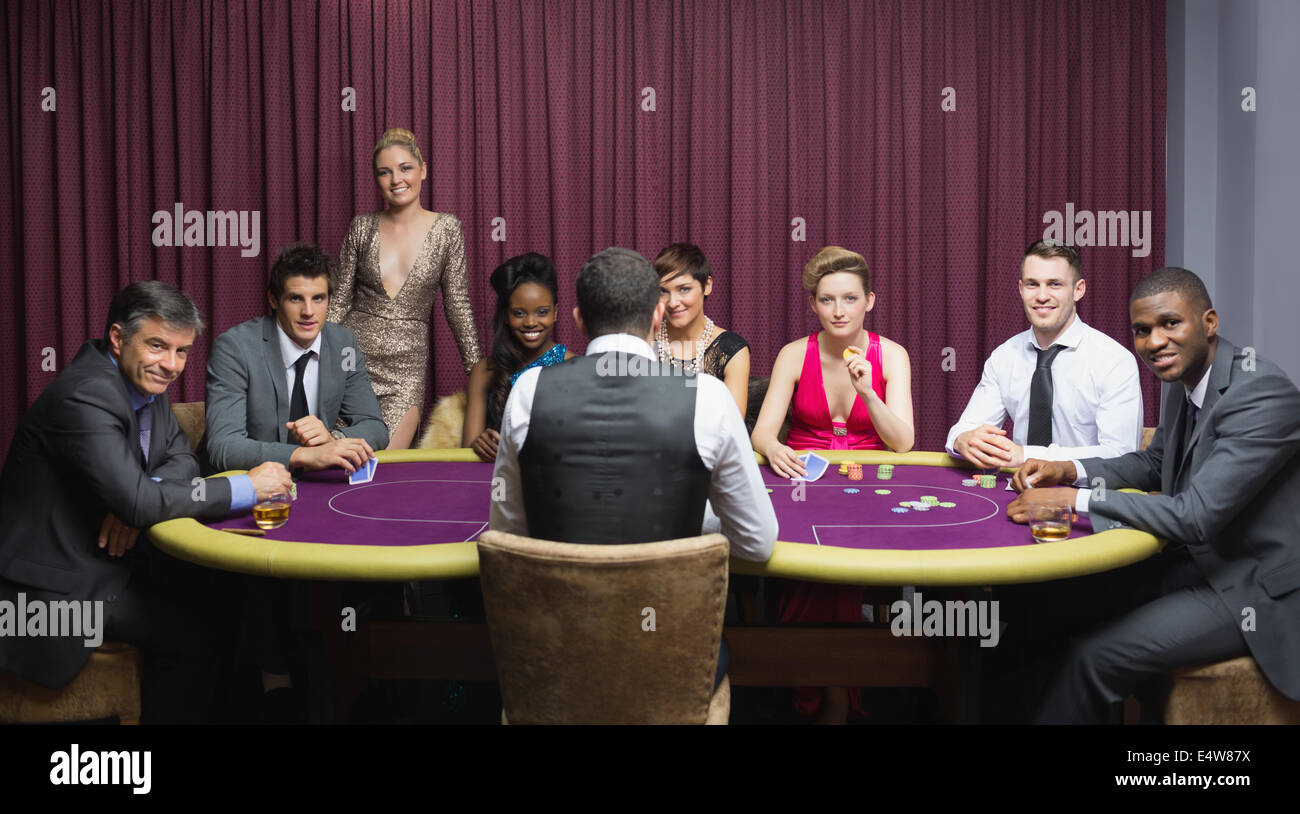 Smiling group sitting around poker table Stock Photo