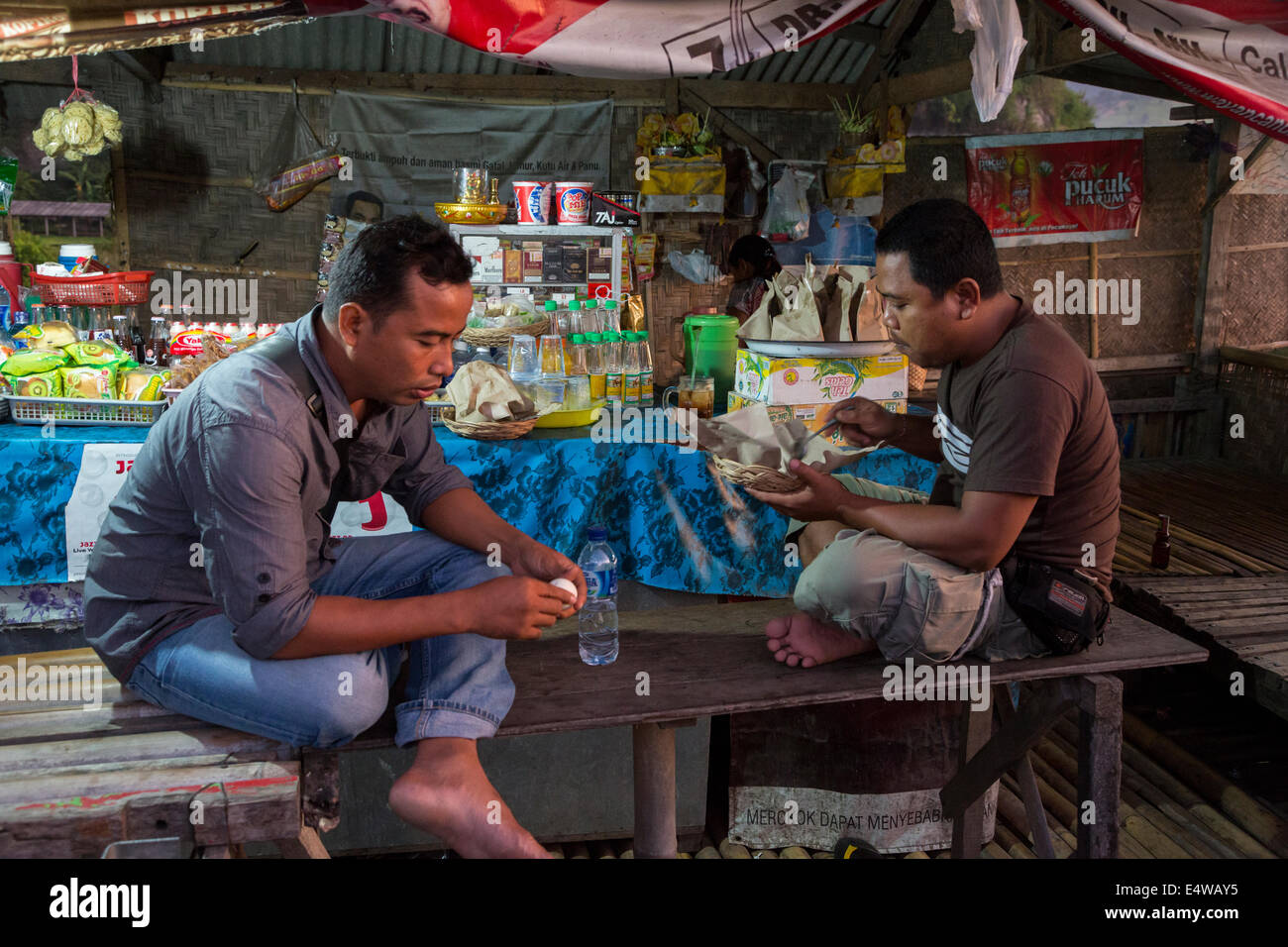 Bali, Indonesia.  Two Men Having Breakfast at a Roadside Refreshment Stand, Early Morning. Stock Photo