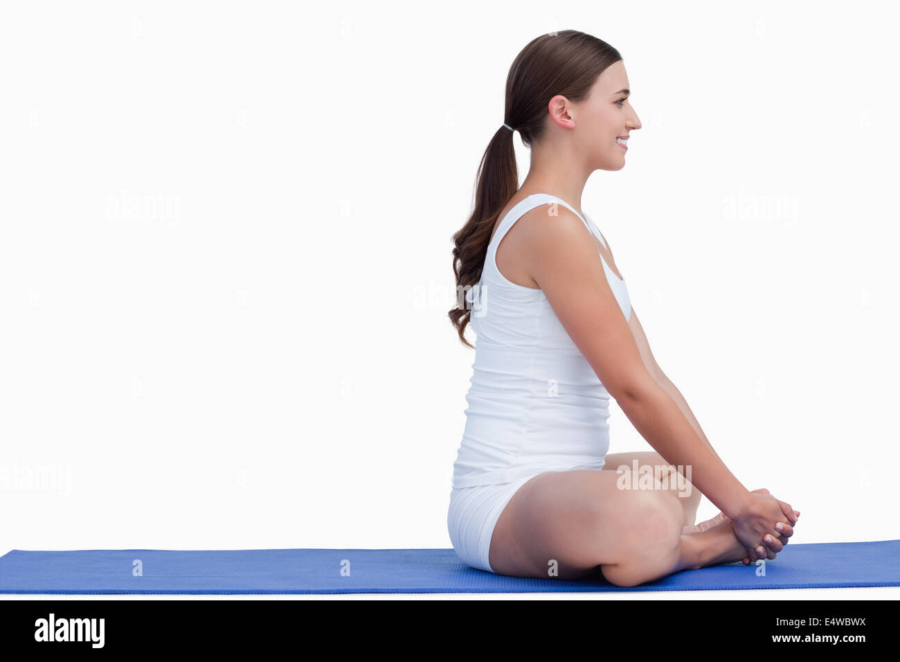 Brunette woman sitting on a yoga mat Stock Photo - Alamy