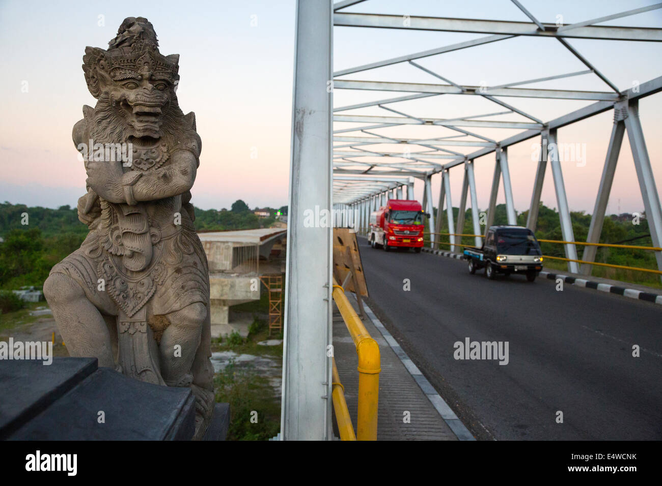 Bali, Indonesia.  Mythical Figure Guards a Bridge in Southern Bali.  New Bridge under Construction in Background. Stock Photo