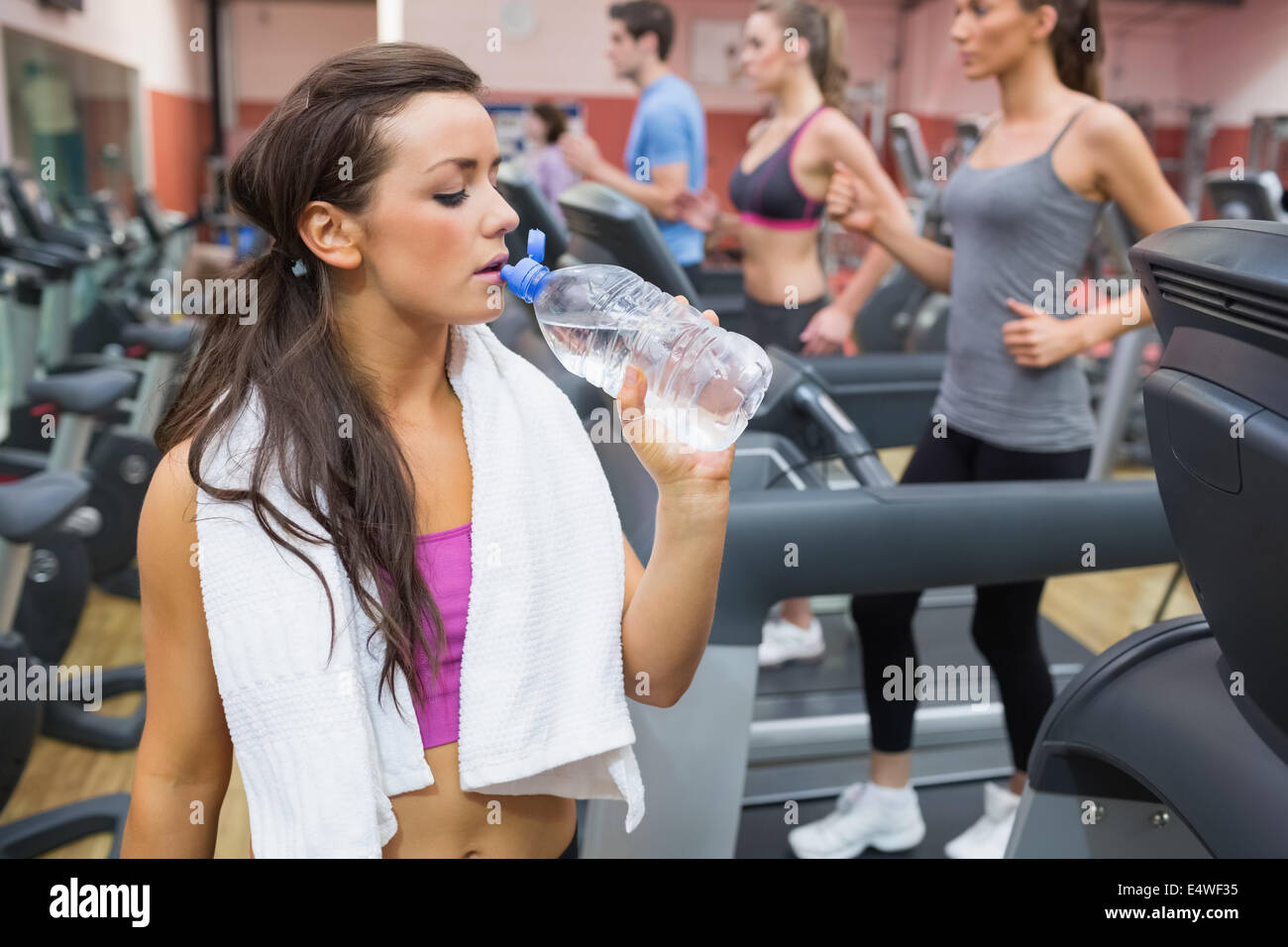 Woman drinking water beside treadmill Stock Photo Alamy