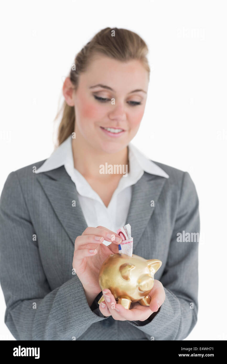 Businesswoman putting money in the piggy-bank Stock Photo