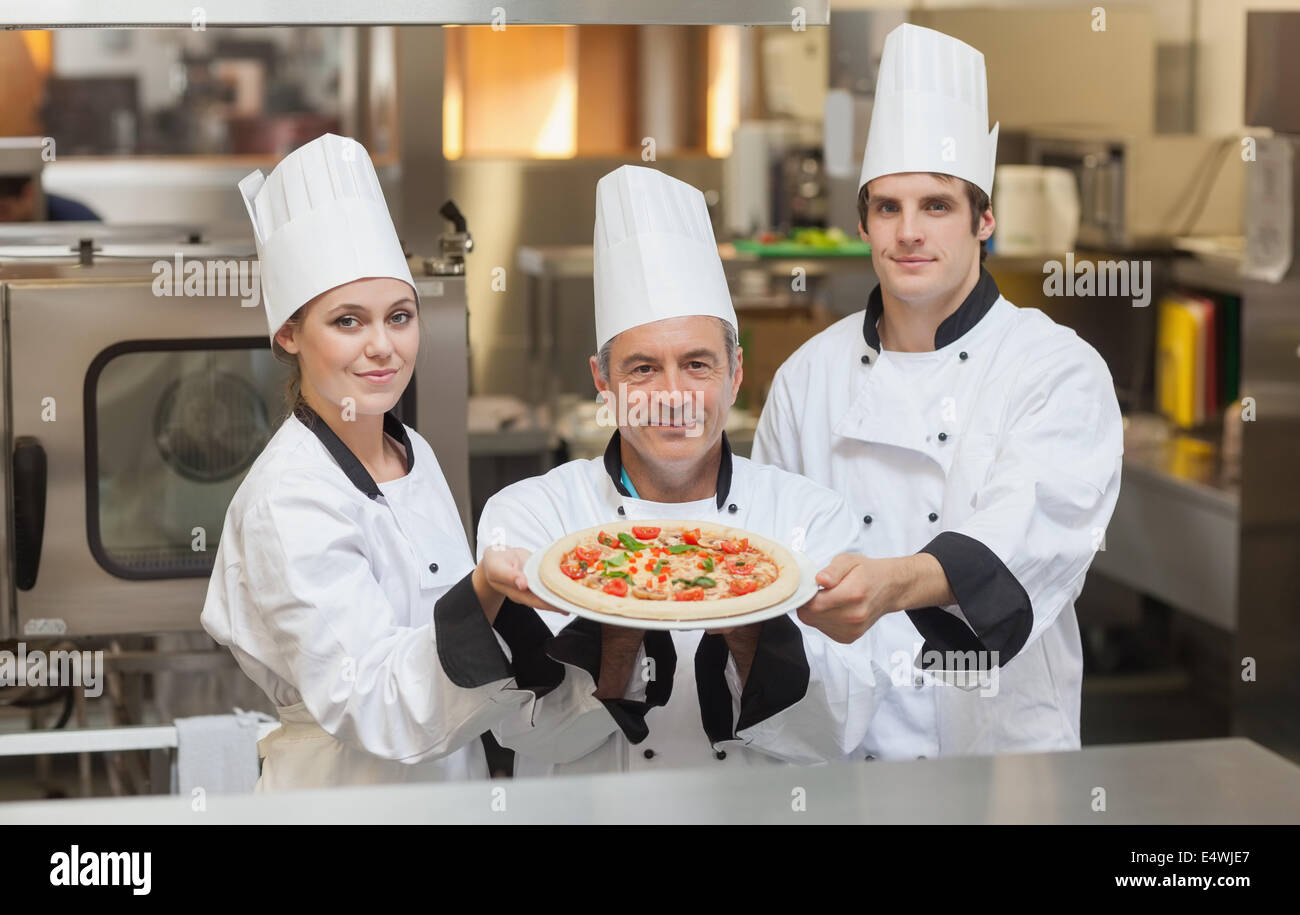 Three Chef's holding a pizza Stock Photo