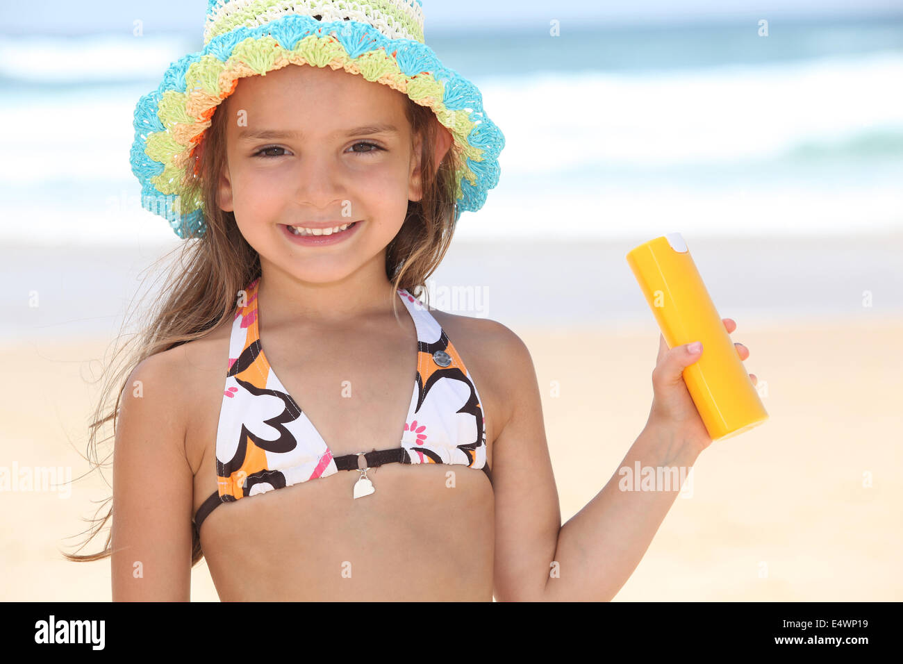 Young girl on the beach holding suncream Stock Photo