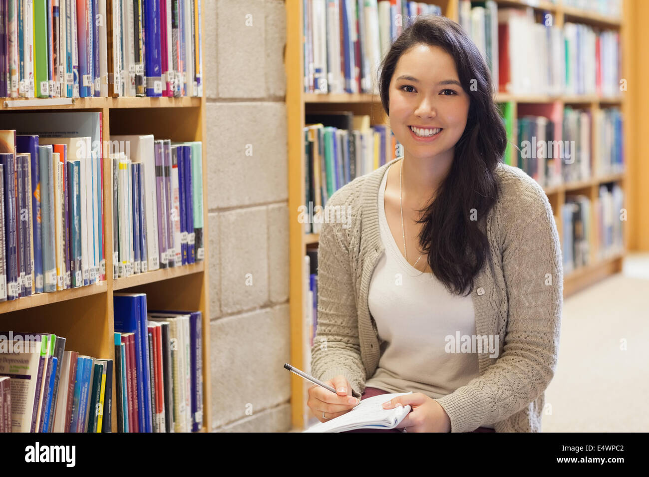 Woman sitting on the library floor smiling Stock Photo - Alamy