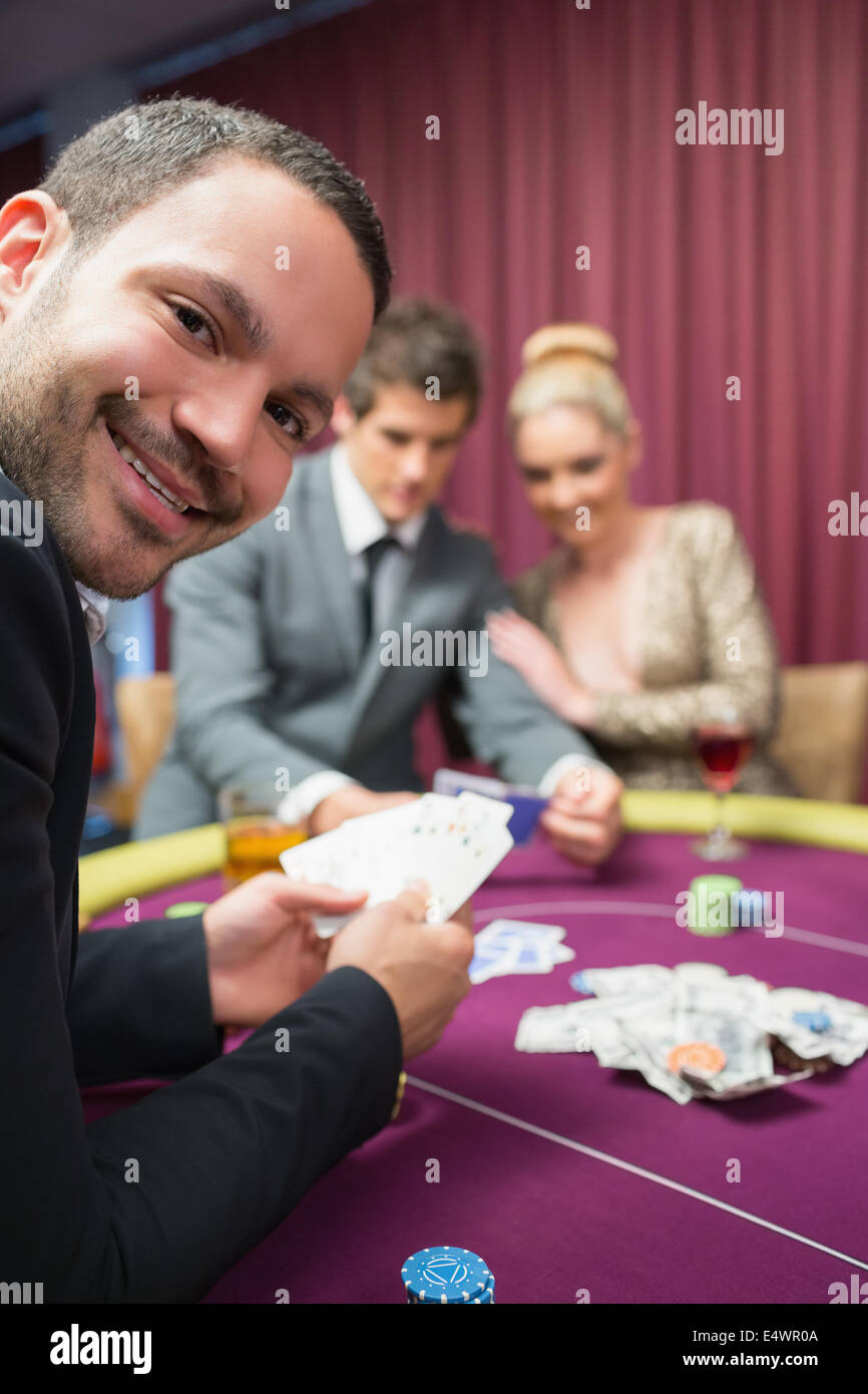 Man smiling while sitting at poker table Stock Photo - Alamy