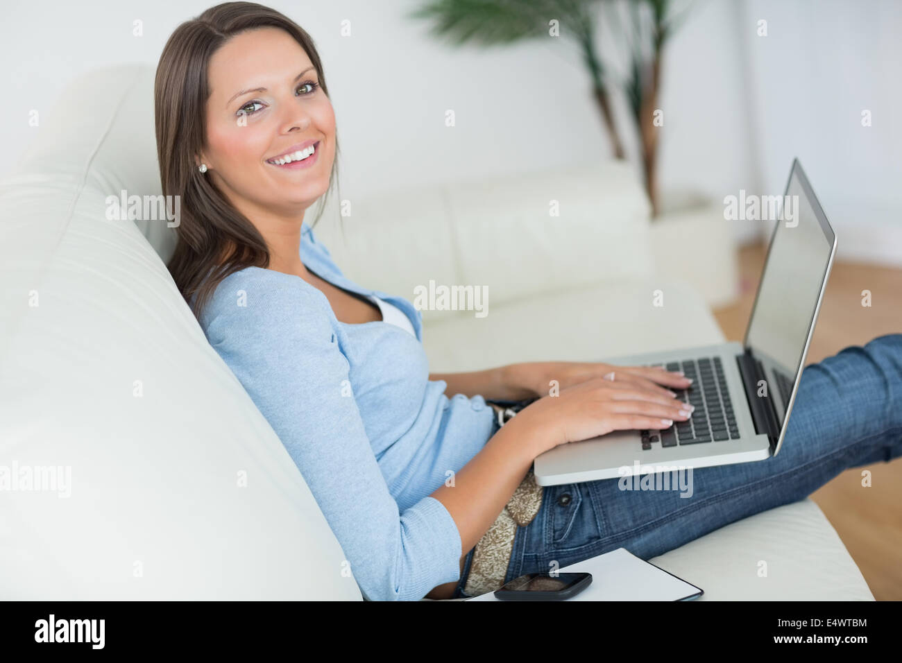 Woman sitting on sofa with her laptop Stock Photo - Alamy