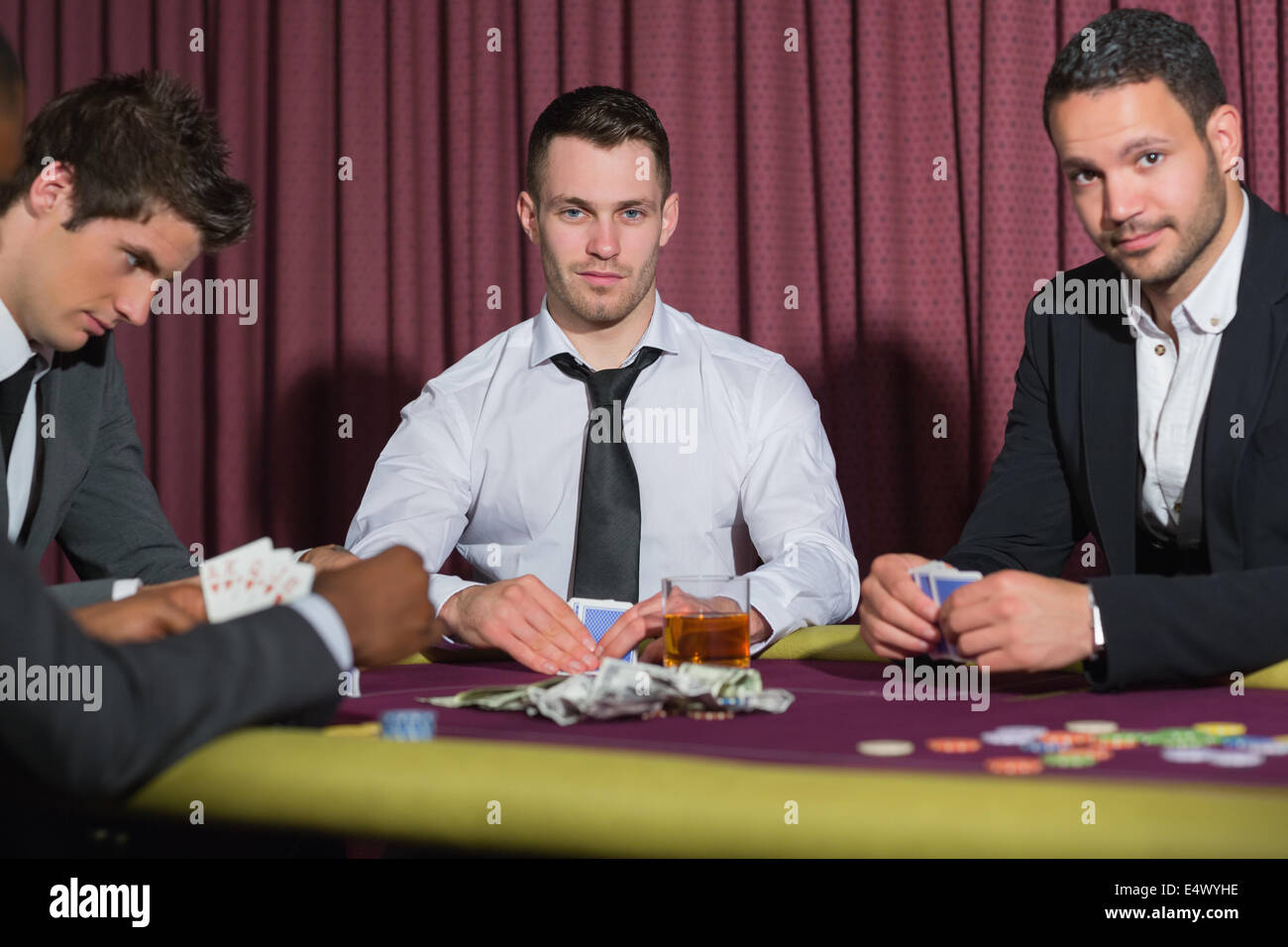 Two smiling men looking up from poker game Stock Photo
