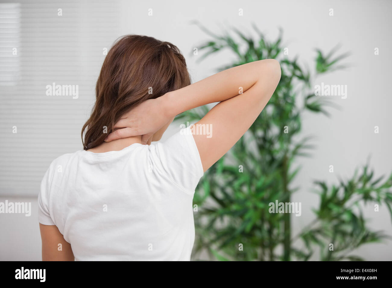 Brunette massaging her painful neck Stock Photo - Alamy