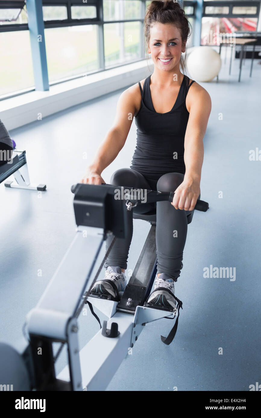 Happy brunette training on row machine Stock Photo - Alamy
