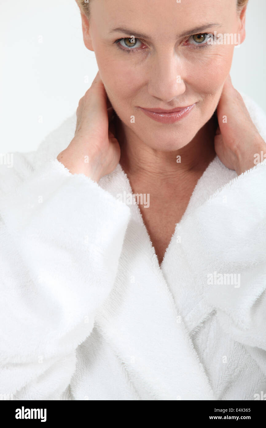 Woman in bath robe with hands behind neck Stock Photo