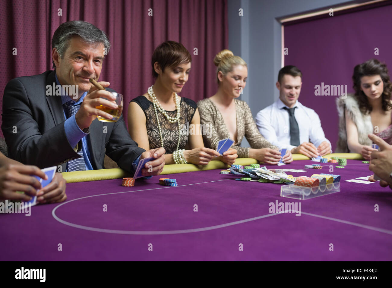 Man with cigar looking up from poker game Stock Photo