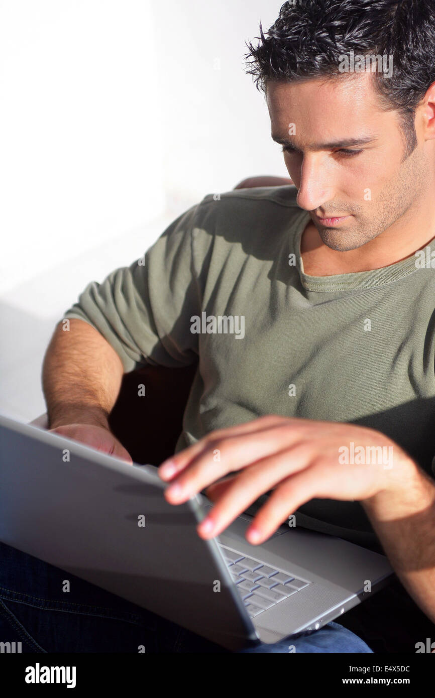 Dark haired man sat with laptop Stock Photo