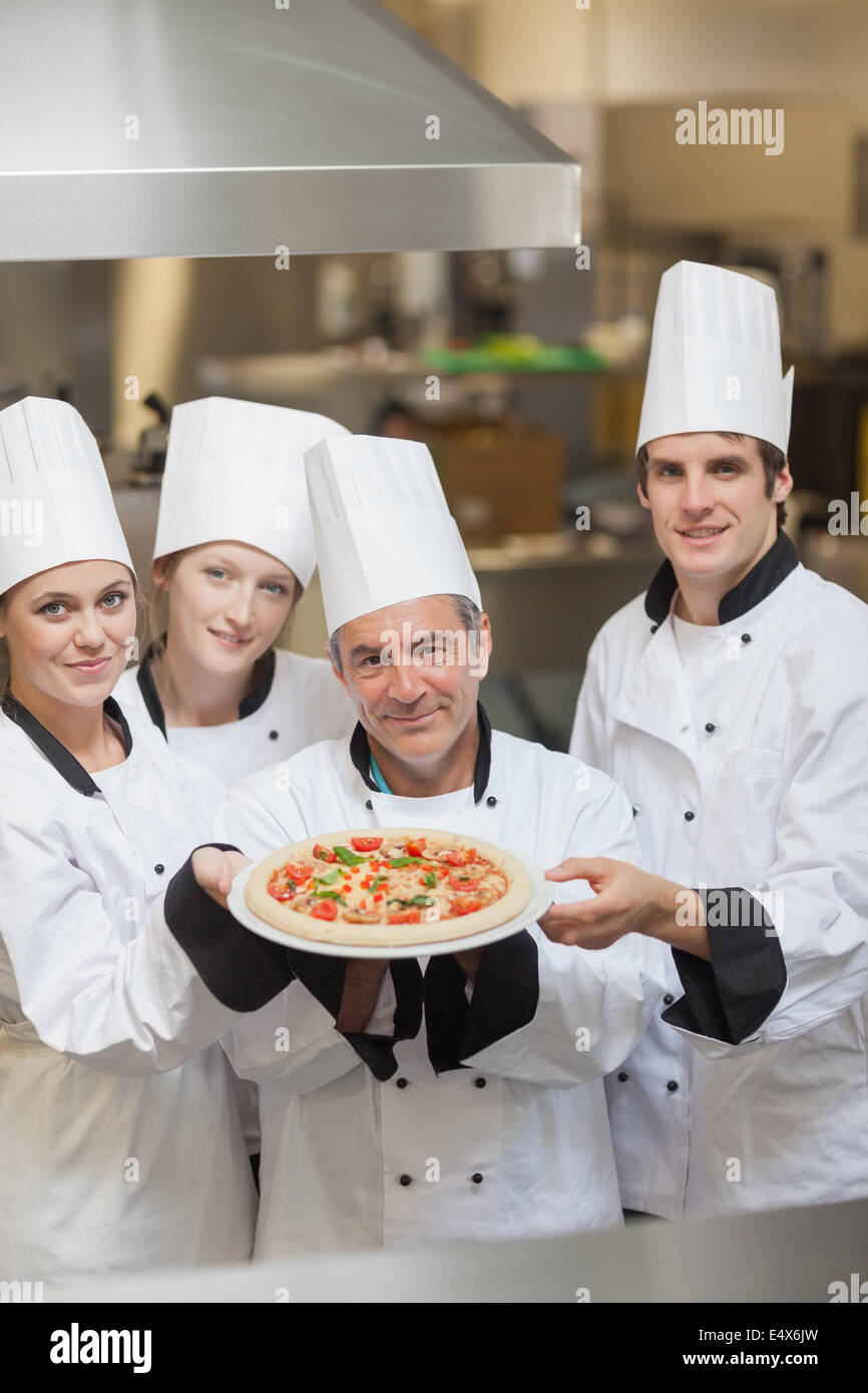 Four Chef's holding a pizza Stock Photo