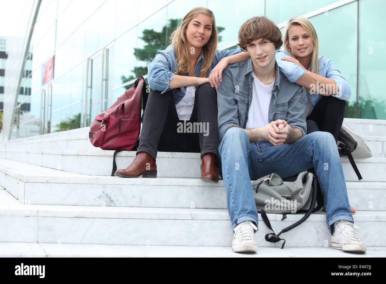 Three students sitting outside on some steps Stock Photo - Alamy