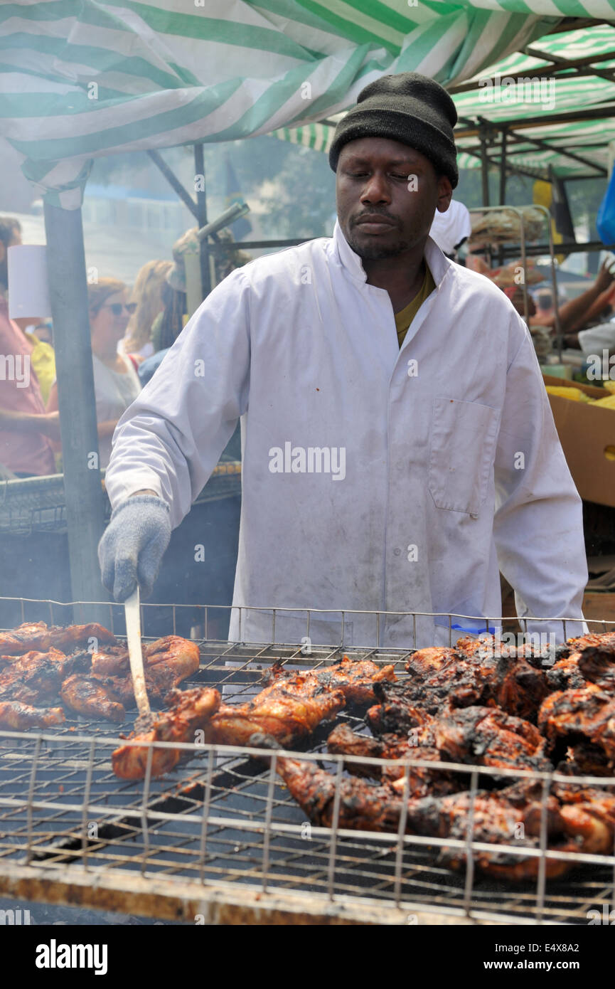 Man cooking chicken pieces on barbecue at Bristol St Paul's street festival, UK Stock Photo