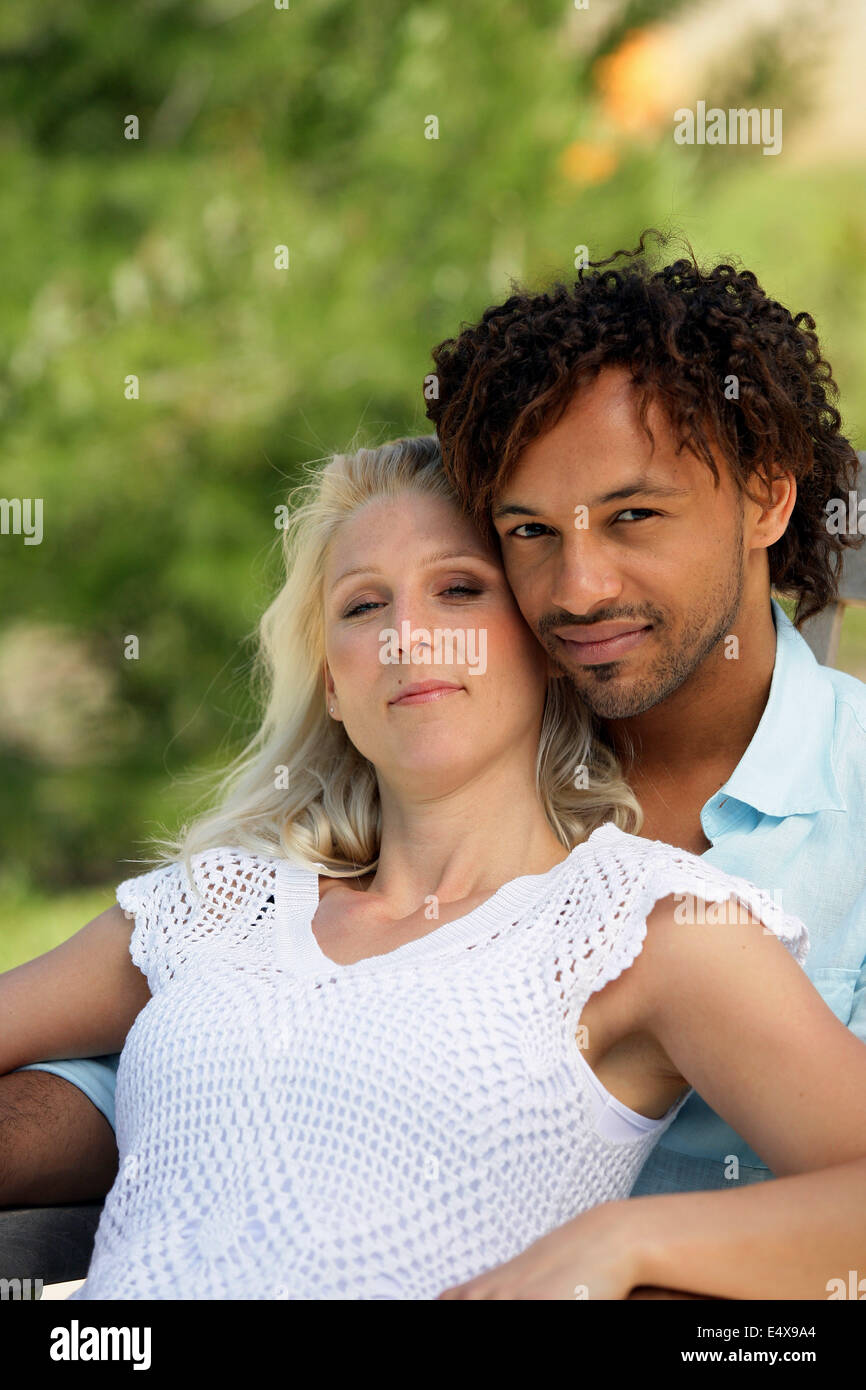 Mixed race couple relaxing in park Stock Photo