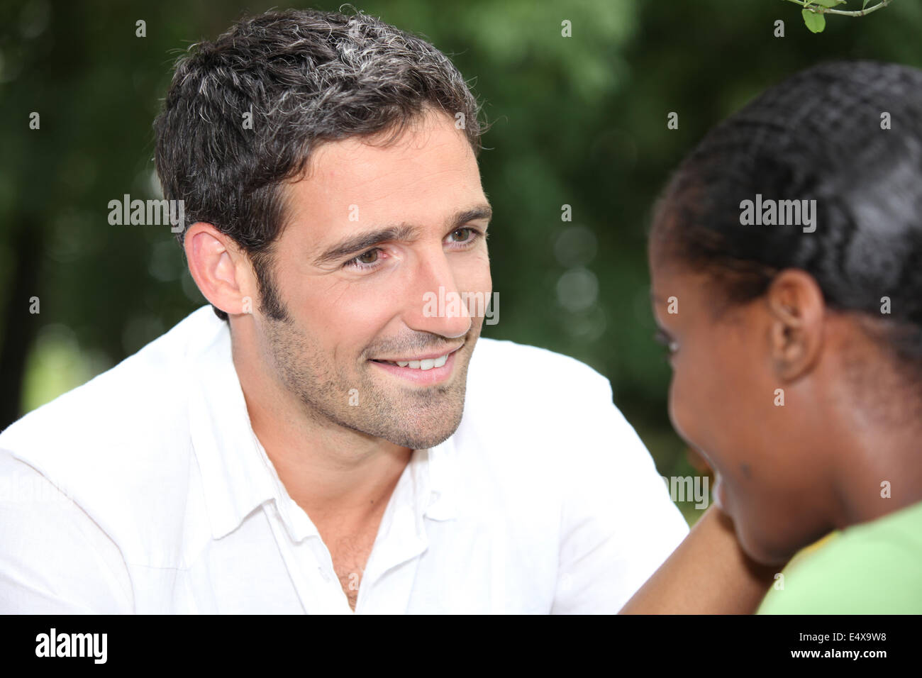 Couple sat chatting in park Stock Photo