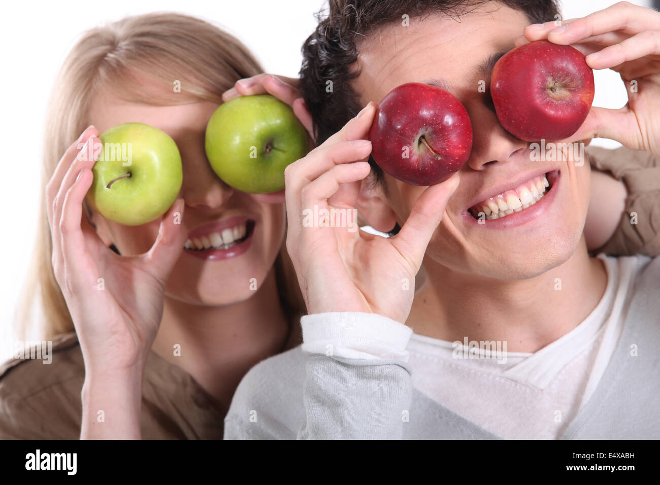 Couple holding up apples to their eyes Stock Photo