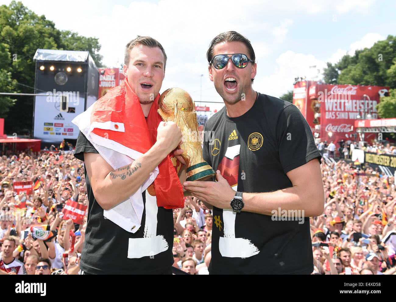 HANDOUT - Germany's Kevin Grosskreutz (L-R) and goal keeper Roman WEIDENFELLER celebrate with the World Cup trophy during the World Cup party at the Brandenburg Gate after team Germany arrived back in Germany in Berlin, Germany, 15 July 2014. The German team won the Brazil 2014 FIFA Soccer World Cup final against Argentina by 1-0 on 13 July 2014, winning the world cup title for the fourth time after 1954, 1974 and 1990. Photo: Markus Gilliar/GES/DFB/dpa (ATTENTION: Editorial use only and mandatory credit "Photo: Markus Gilliar/GES/DFB/dpa") Stock Photo