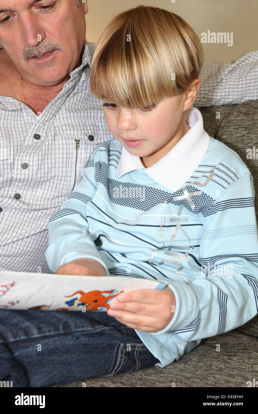 Man reading a book to a little boy Stock Photo