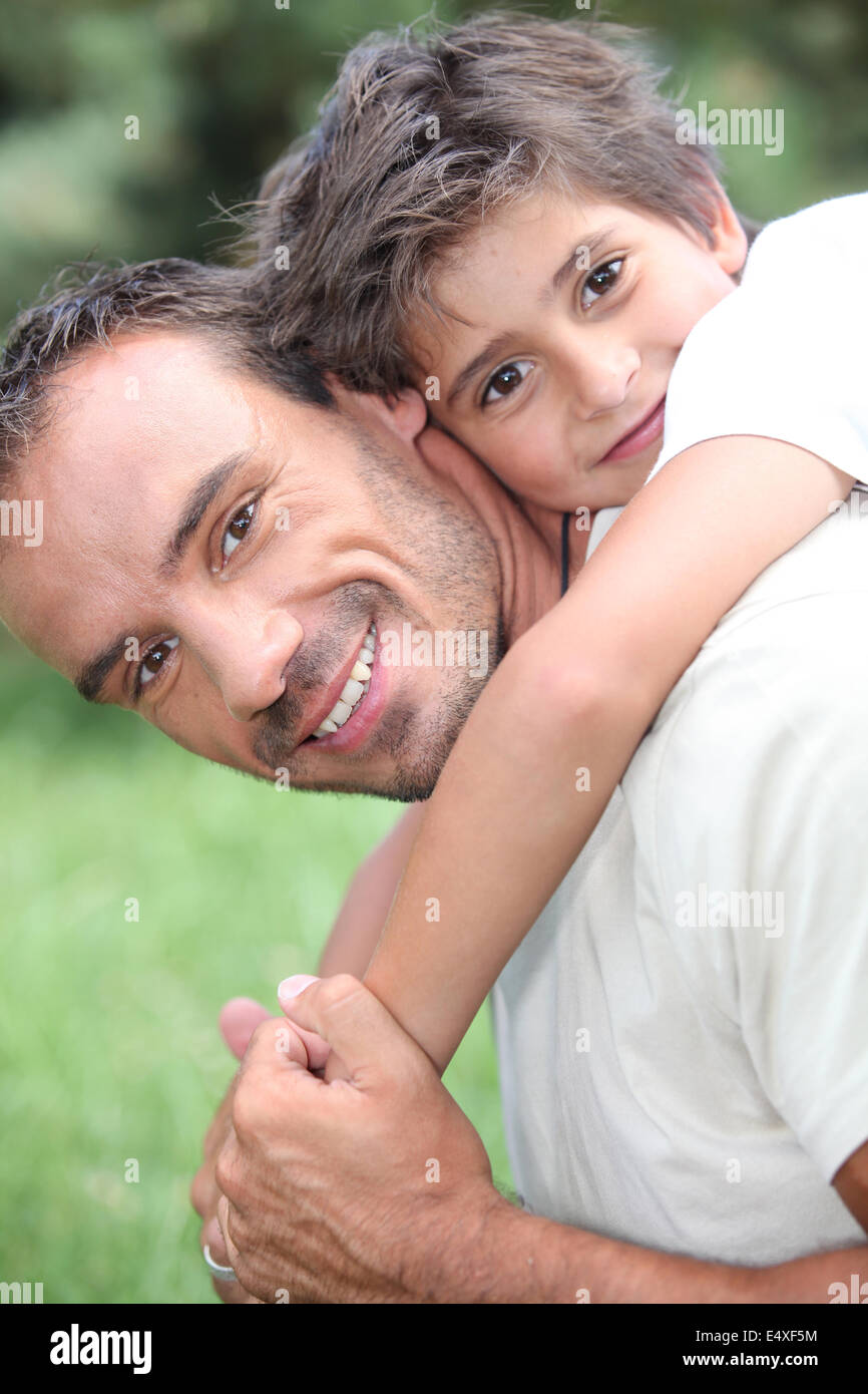 Father giving son piggy back outdoors Stock Photo
