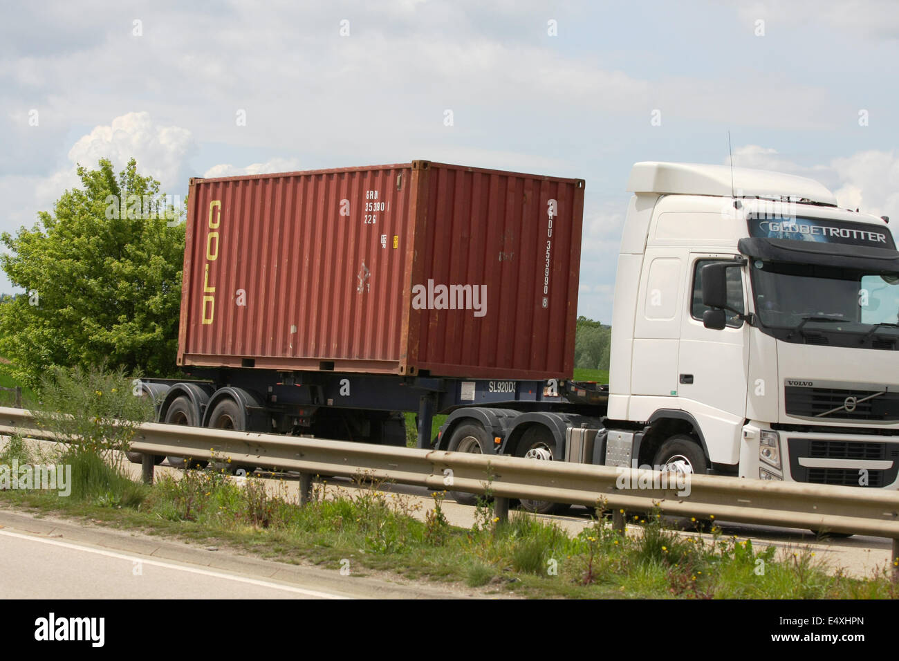 A Volvo Globetrotter truck hauling a Gold shipping container along the A12 dual carriageway in Essex, England Stock Photo