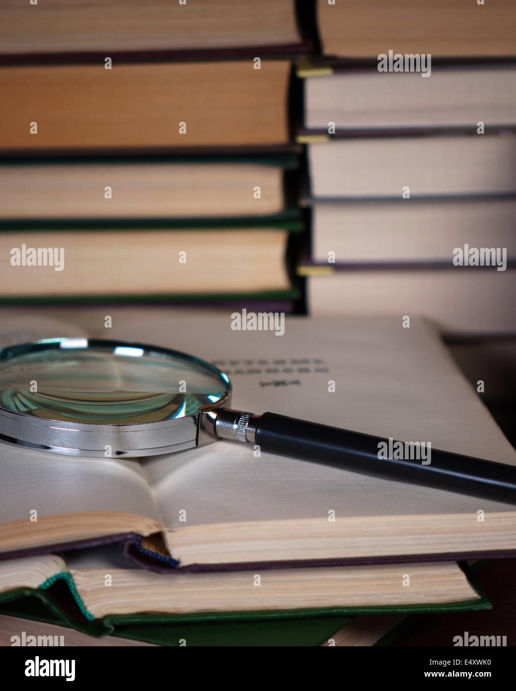 Magnifying glass on a pile of open books. Stock Photo