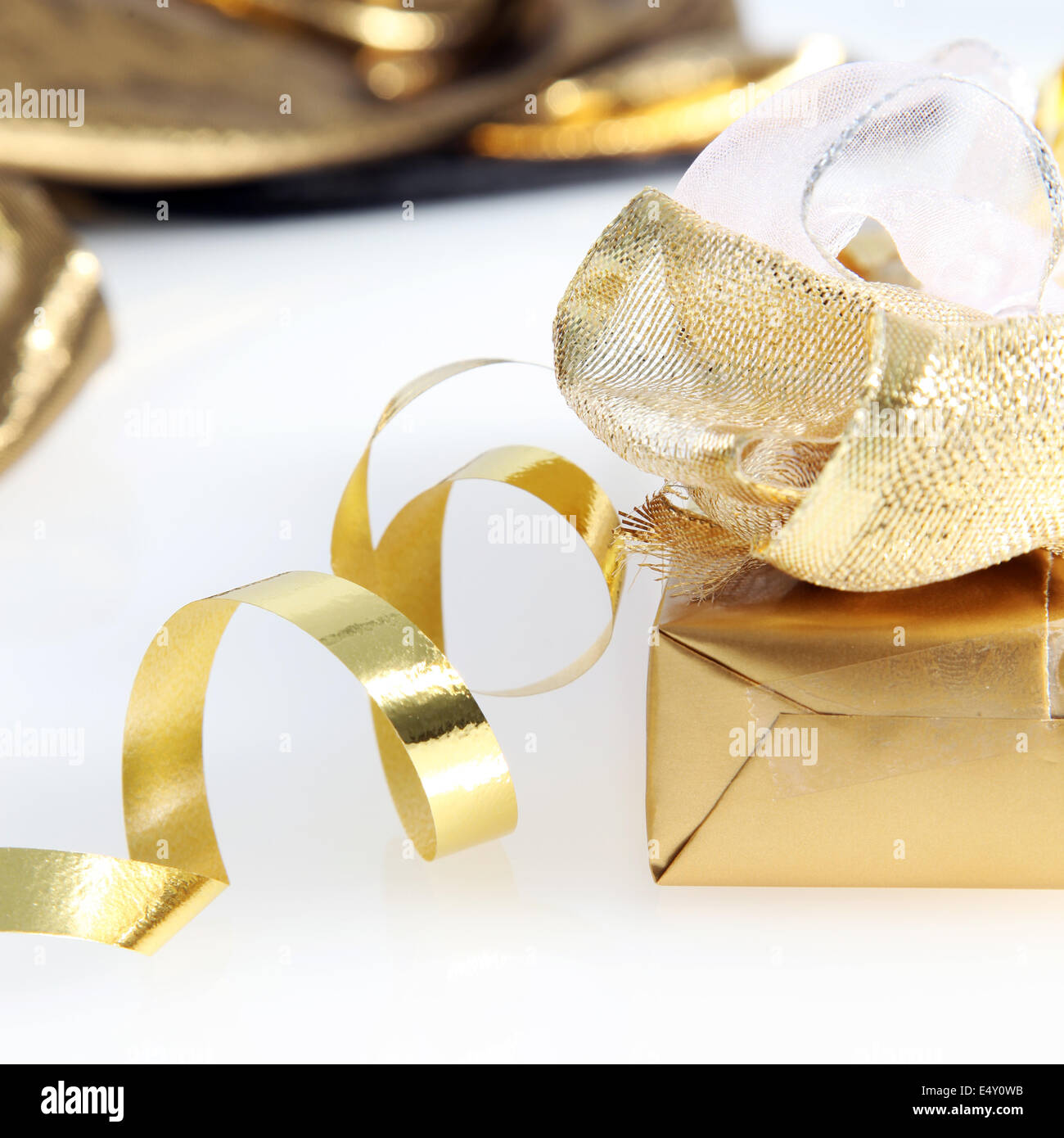 Pretty gold wrapped gift and twirled ribbon Stock Photo