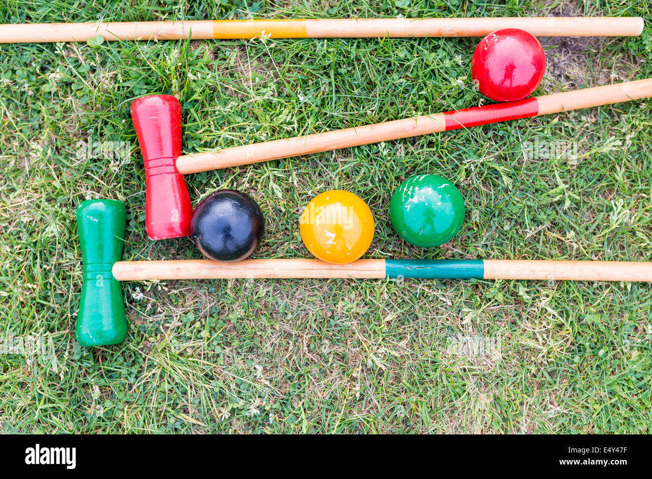 Clubs and balls belonging to a croquet game lying on green grass Stock Photo