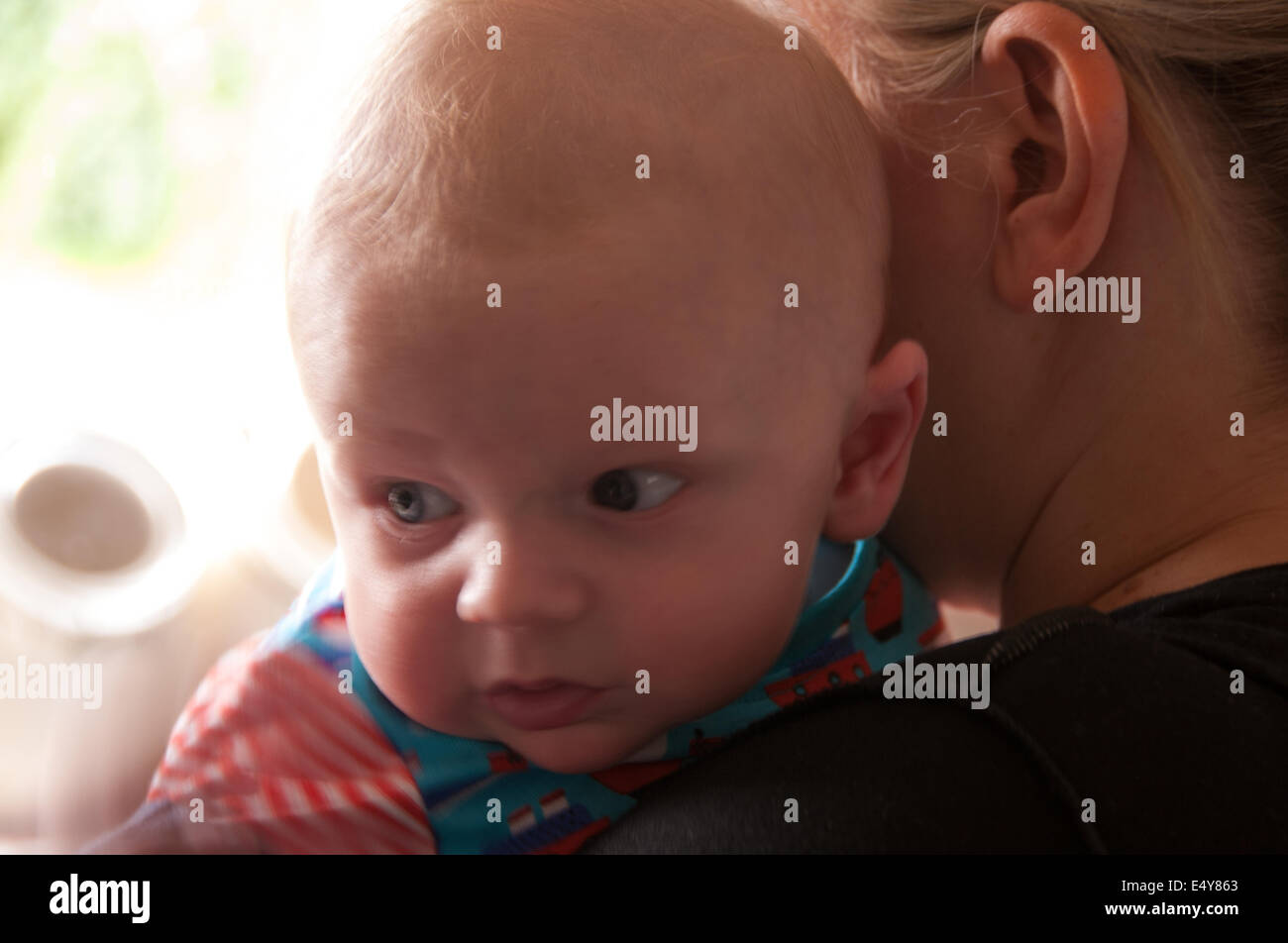 Mother holding baby over shoulder Stock Photo