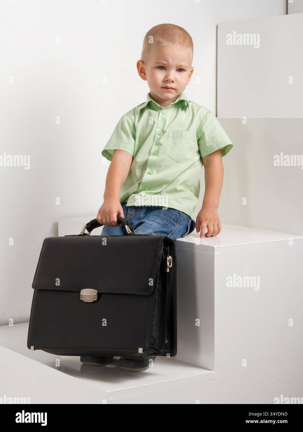 sad kid with briefcase on stairs on light background Stock Photo