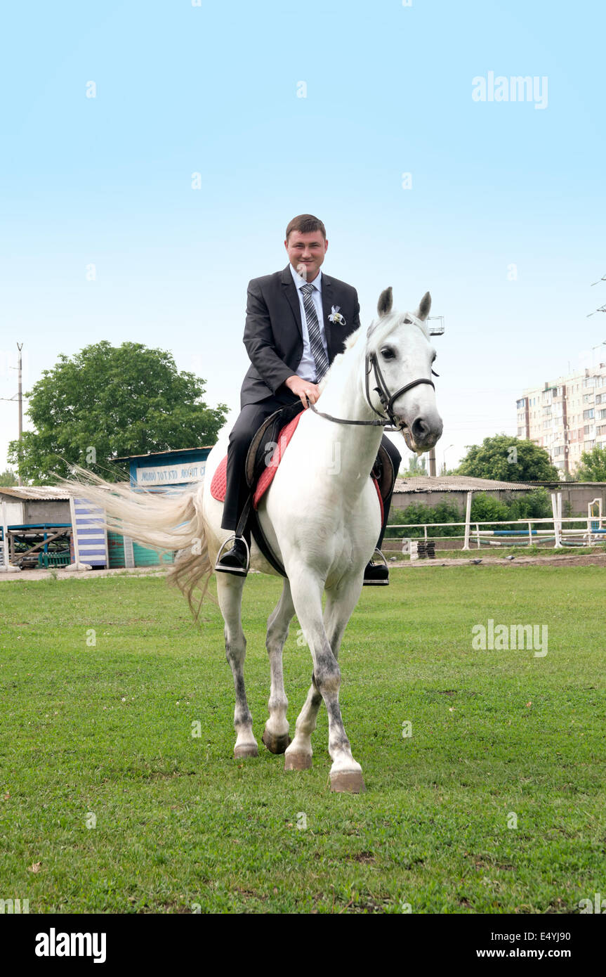 The young groom riding on a white horse Stock Photo Alamy
