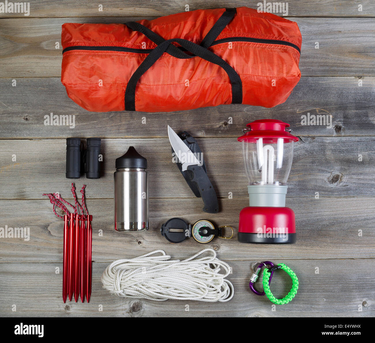 Overhead view of basic hiking gear placed on weathered wooden boards. Items  include tent inside of bag, pegs, compass, canteen Stock Photo - Alamy