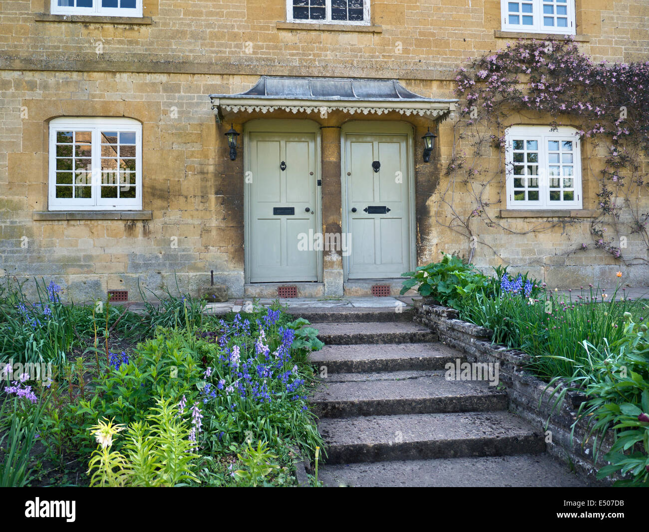 Typical stone Cotswolds cottages with shared entrance and identical front doors close together Stock Photo