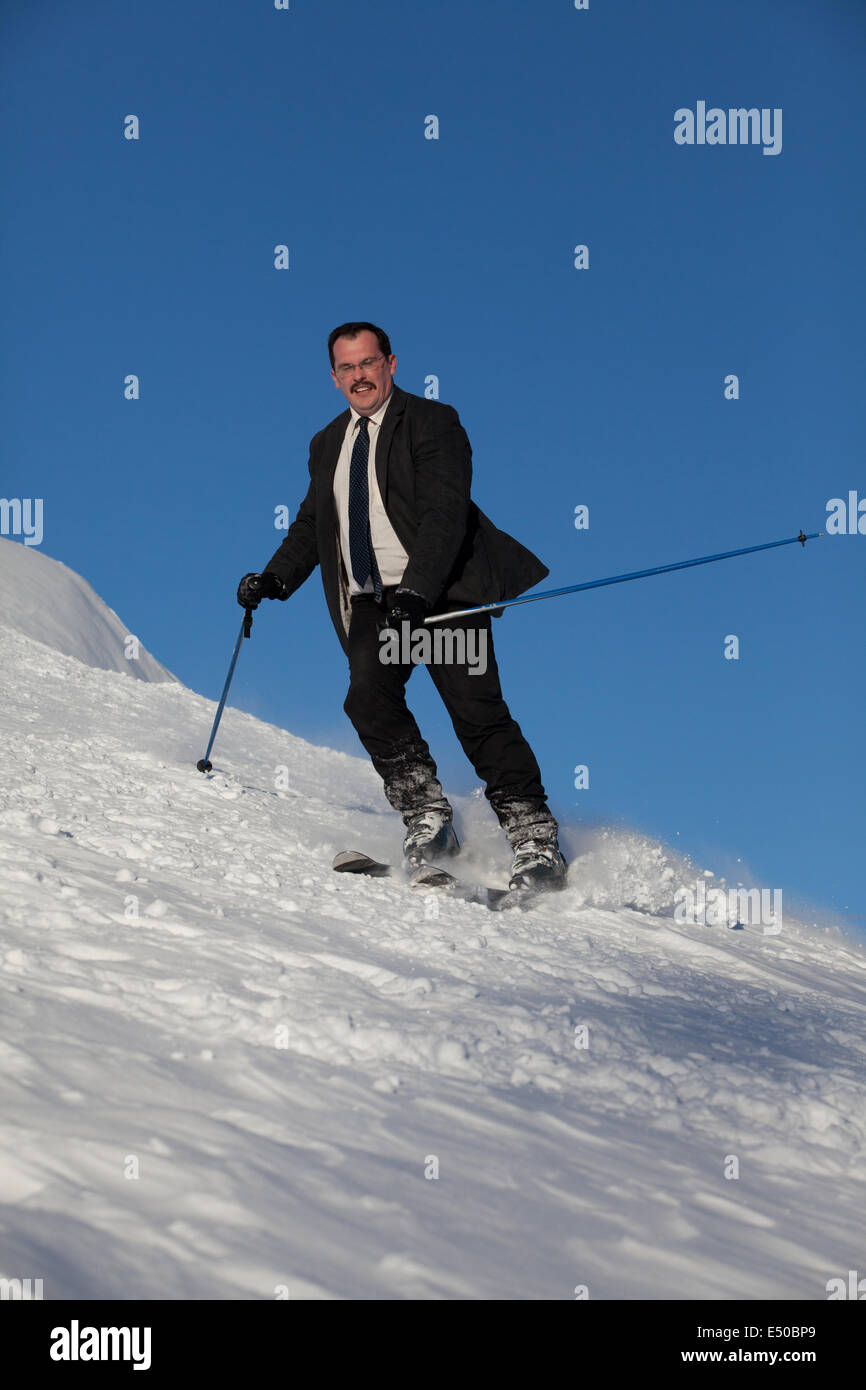 Man in business sute on ski going down Stock Photo