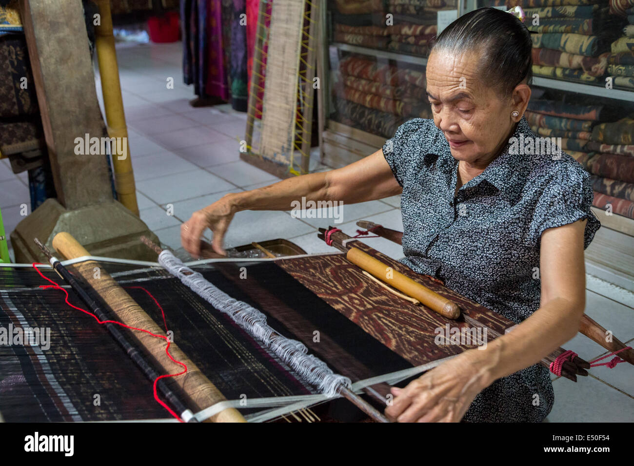 Bali, Indonesia.  Woman Weaving Using Back-strap Loom to Weave  Geringsing Cloth, a Specialty of Tenganan Village. Stock Photo
