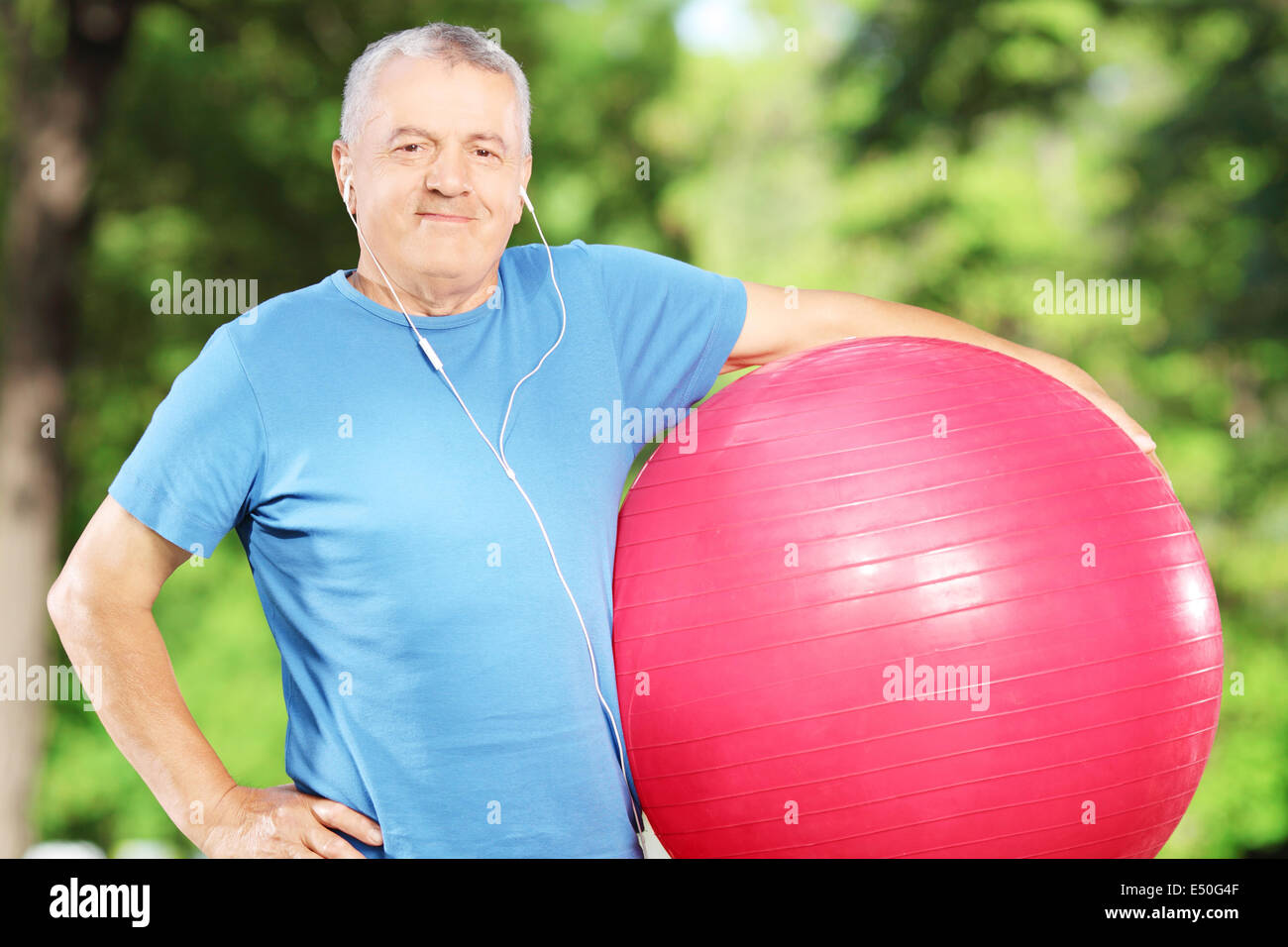 Mature sporty man holding a fitness ball in park Stock Photo