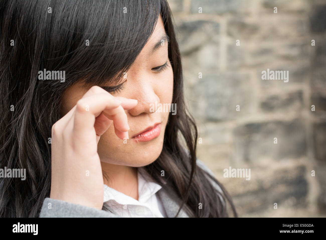 Sad woman by a stone wall Stock Photo