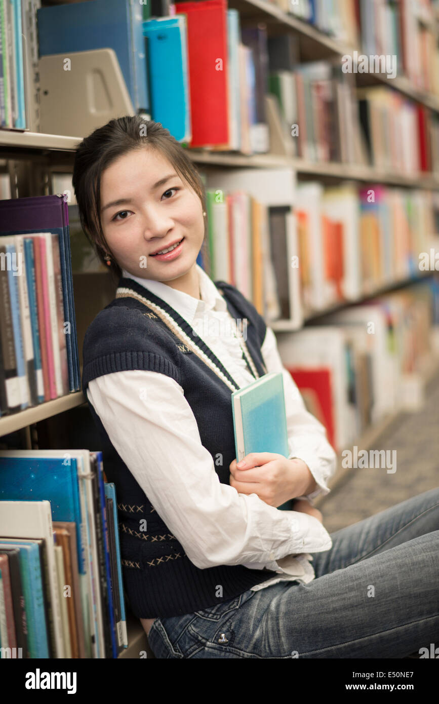Girl huggering a book near bookshelf Stock Photo - Alamy