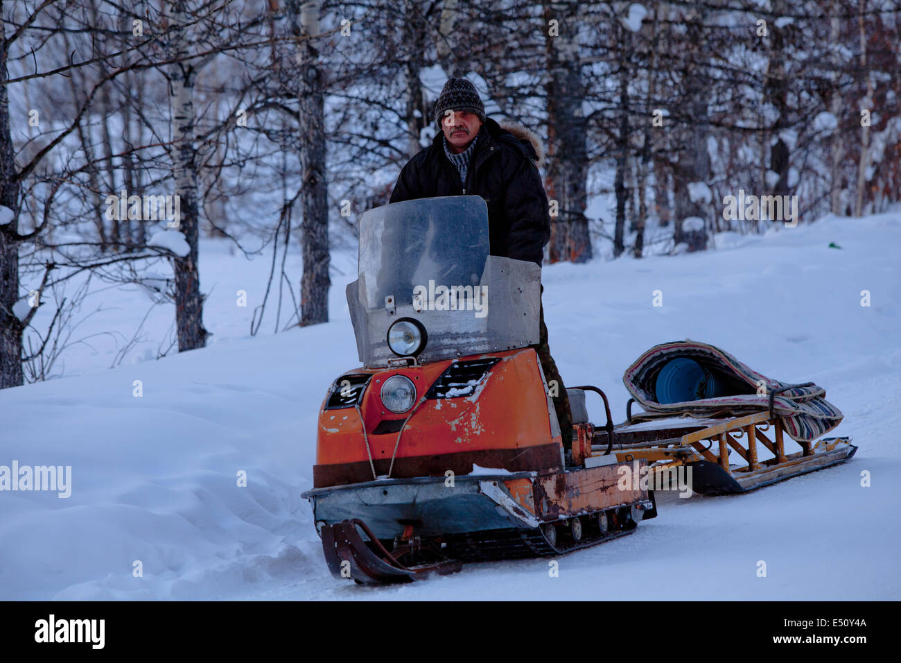 Russian man on snowmobile with sledge behind Stock Photo Alamy