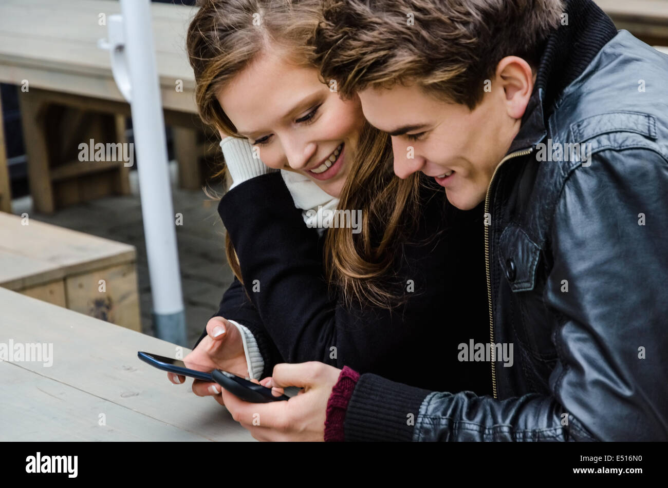 Loving Couple Using Mobile Phone At Bench Stock Photo