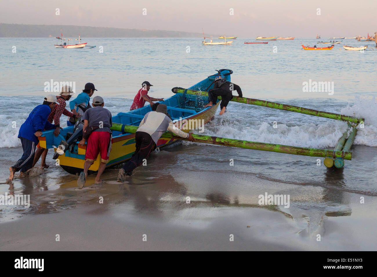 Jimbaran, Bali, Indonesia.  Fishermen Launching a Boat, Early Morning. Stock Photo