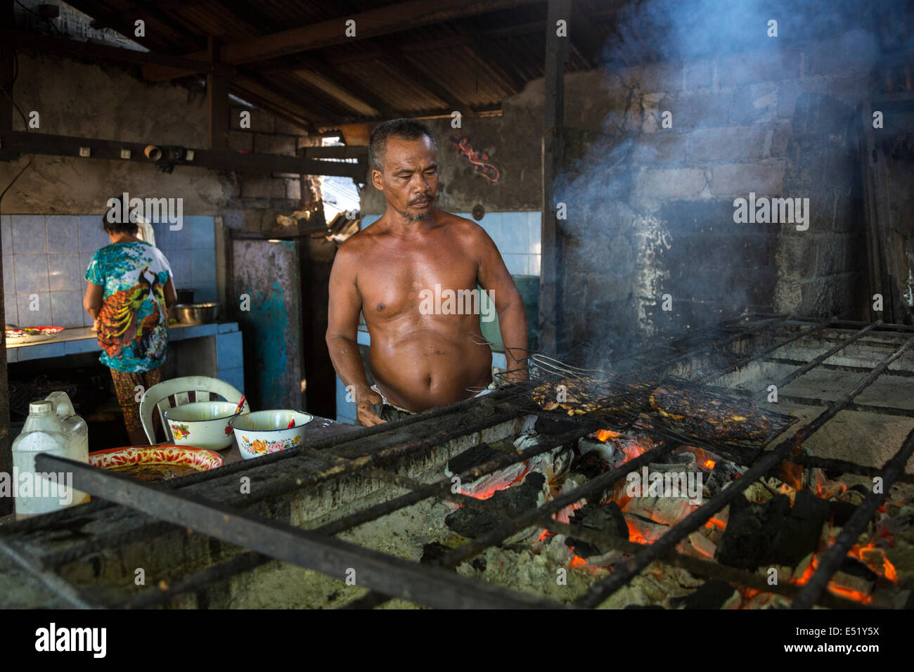 Bali, Indonesia.  Cook Grilling Fish over Charcoal Fire, Jimbaran Fish Market. Stock Photo