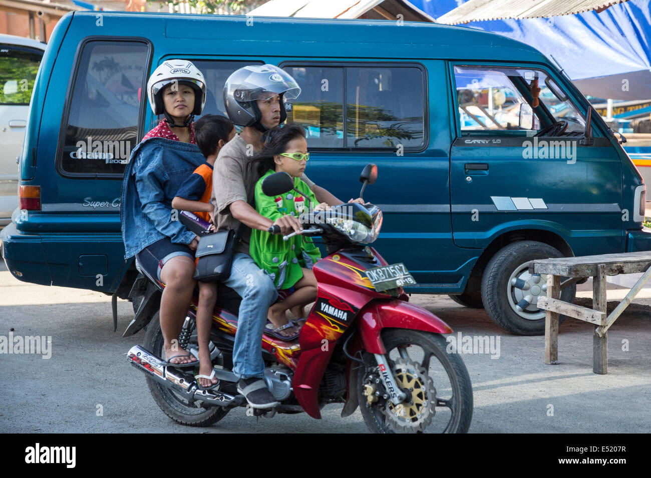 Jimbaran, Bali, Indonesia.  Family on Motorbike.  Adults with Helmets, Children Without. Stock Photo
