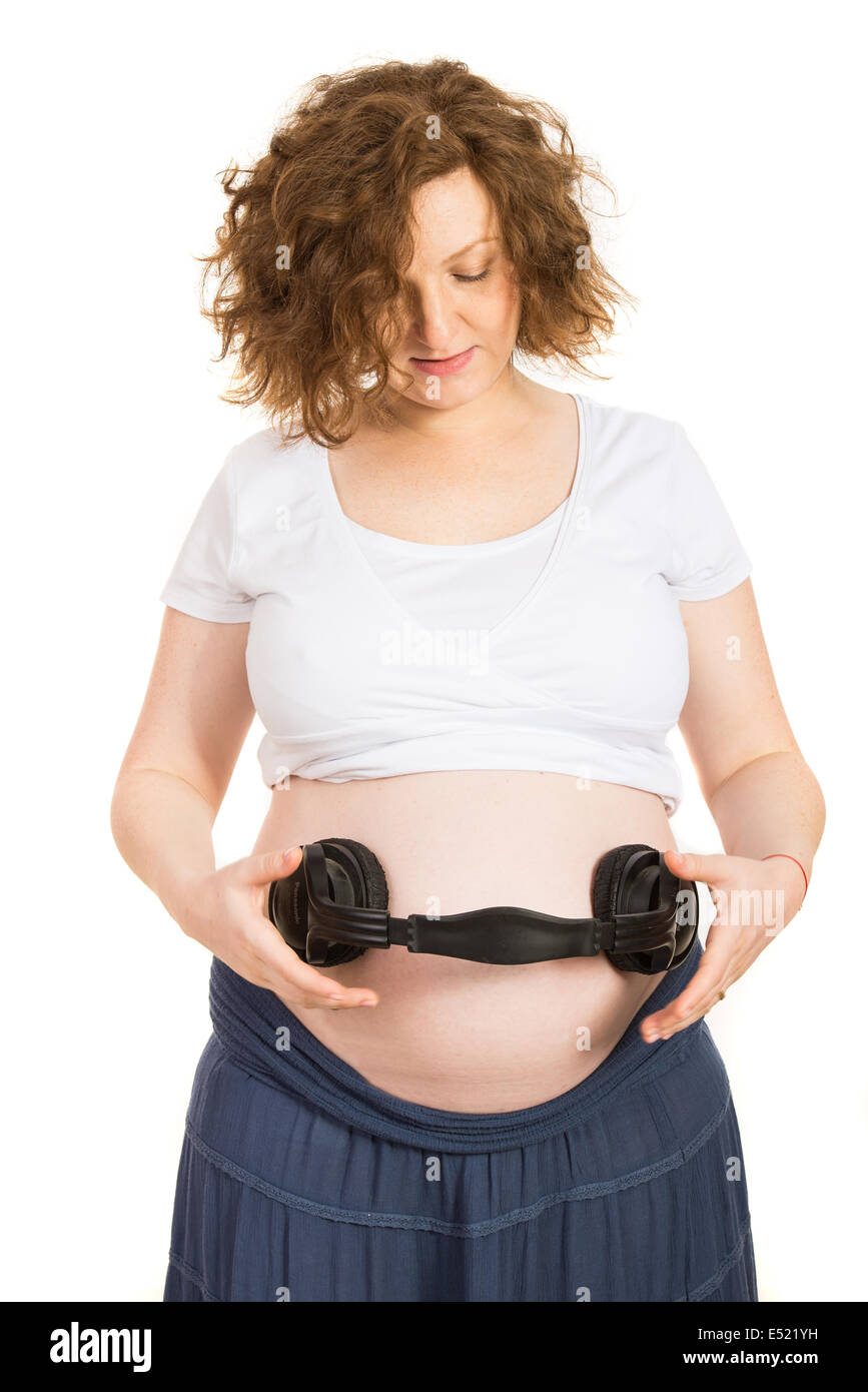 Pregnant belly listening music in headphones isolated on white