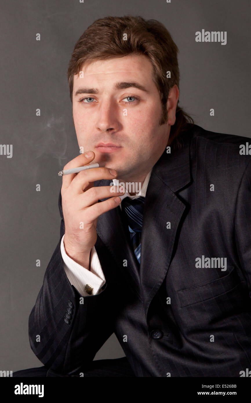 man in a business suit smoking a cigarette Stock Photo