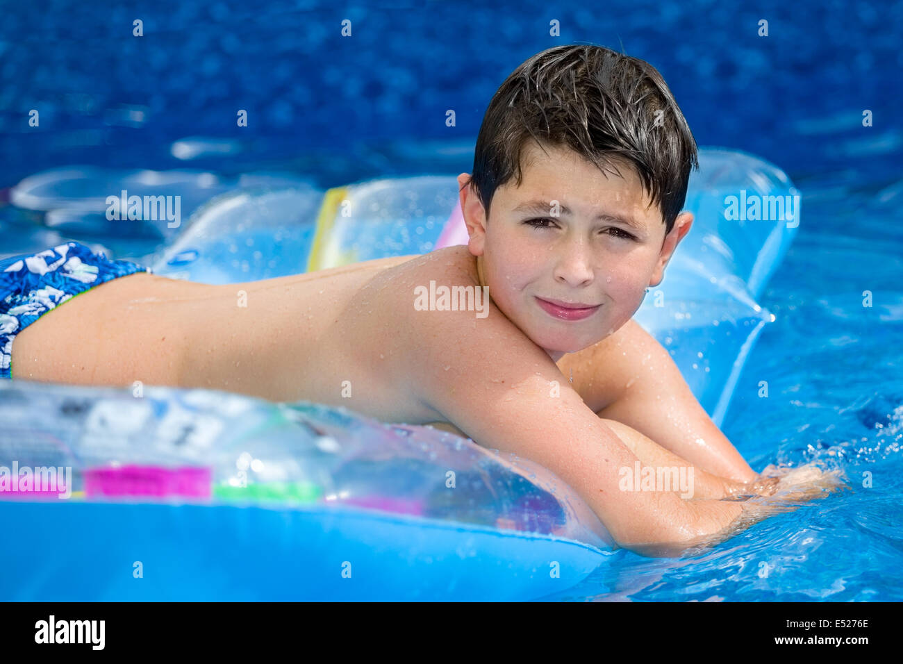 Happy young boy with inflatable water lounger in the swimming pool Stock Photo